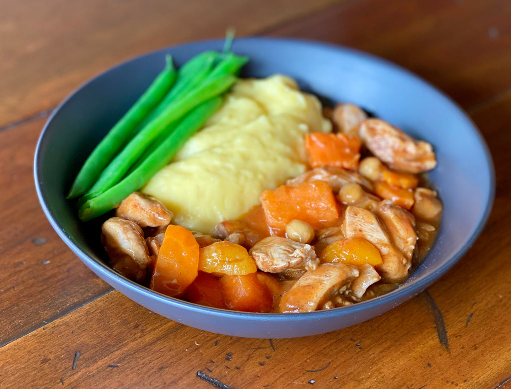 bowl of chicken tagine served with mash and green beans