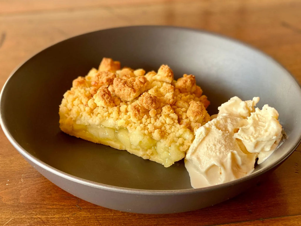 bowl of classic apple crumble served with vanilla ice cream