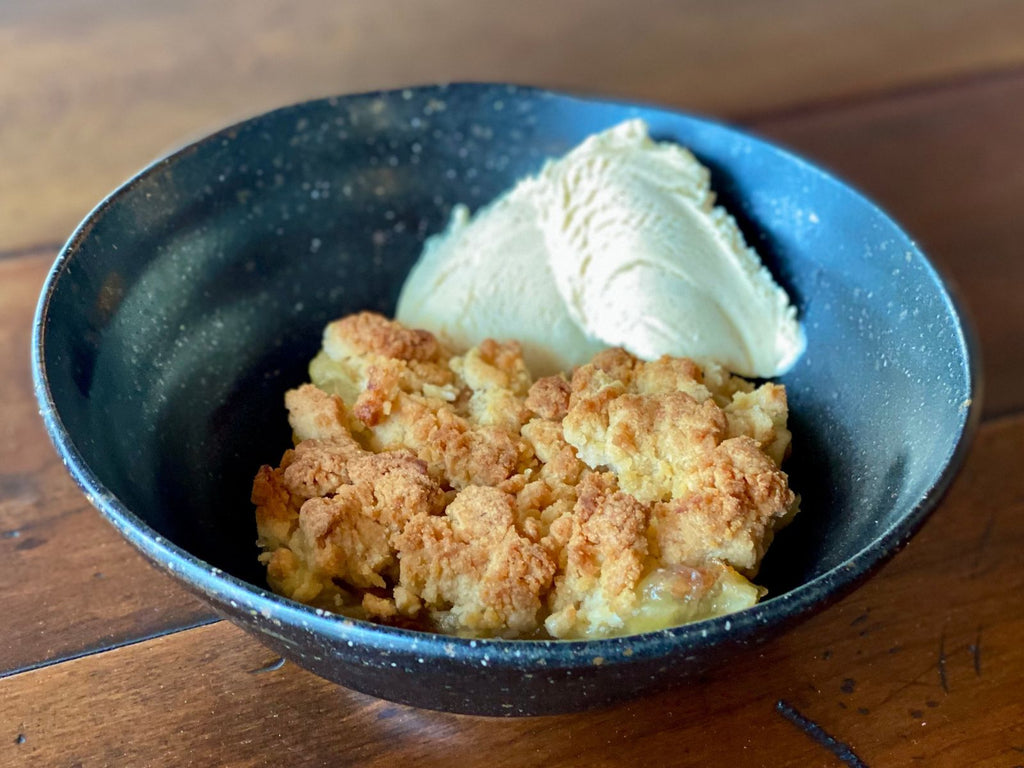 bowl with a slice of apple crumble and vanilla ice cream