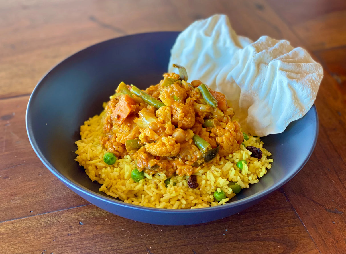 bowl of indian vegetable curry served with pilau rice and pappadum
