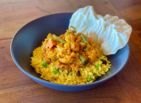 bowl of indian vegetable curry served with pilau rice and pappadum