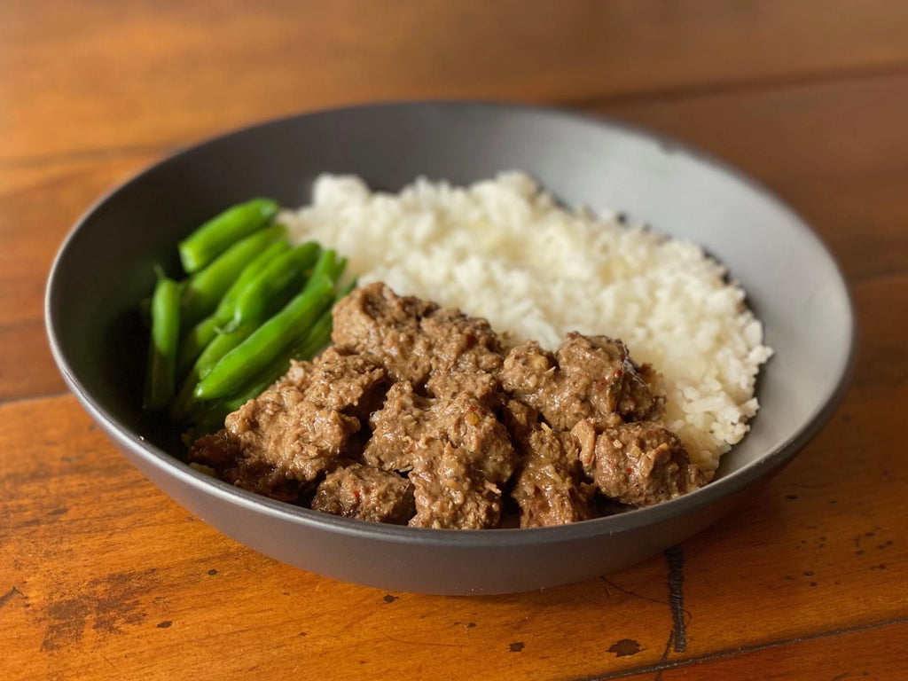 bowl of malaysian beef rendang served with coconut rice and green beans