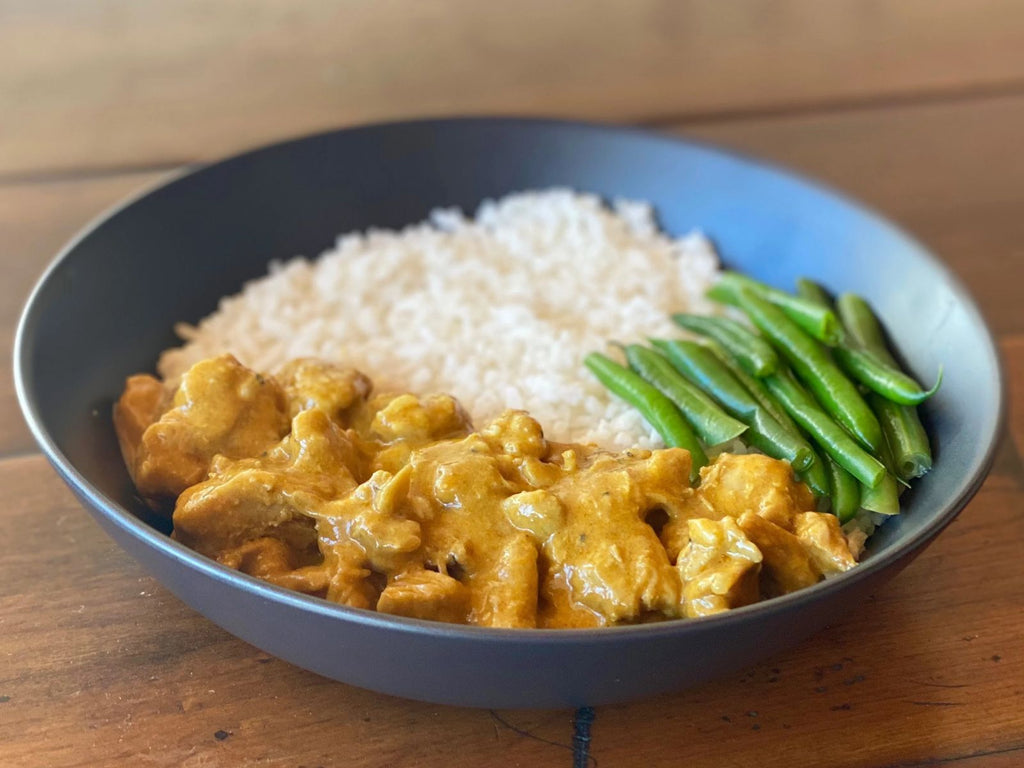 bowl of malaysian chicken curry served with green beans and coconut rice